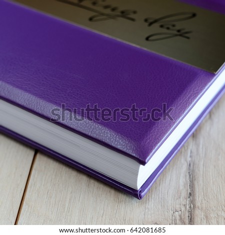 Wedding book in purple wrapper on a wooden background
