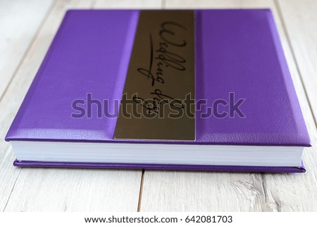 Wedding book in purple wrapper on a wooden background