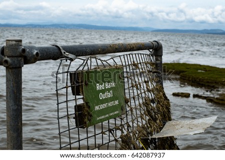 Sign attached to old metal coastal fence - Incident hot line