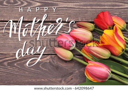 Happy mothers day greeting card lettering tulips flowers Photo with handwritten inscription Happy Mother's Day, red and yellow tulips on natural wooden background 