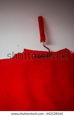 Red paint on a white wall with paint roller