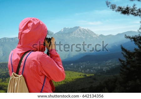 Girl traveler takes the photo of mountain on background.
