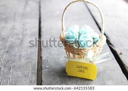 Spring sale tag and flowers in a small basket, copy space. Composition on the old table.