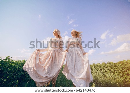 young beautiful twins of vintage dresses in the field