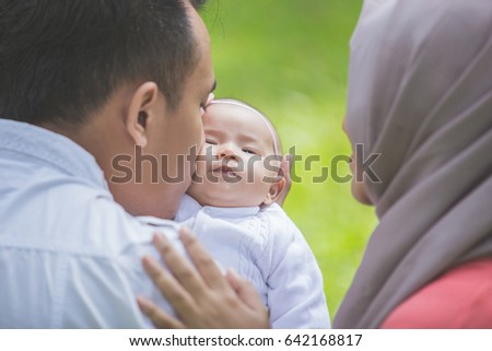 portrait of happy Father and mother with their newborn baby in park