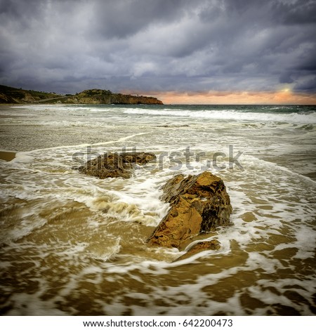 This rock formation along the beach provides a leading line to the beautiful orange horizon forming underneath the dark cloudy sky in this Southern California beach