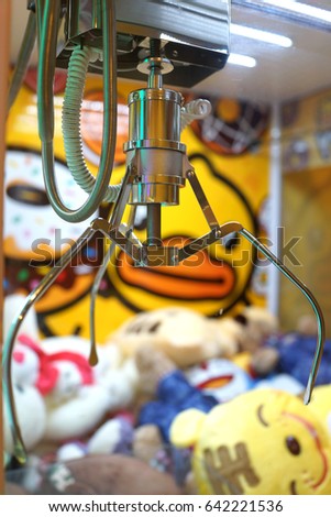 Capture device for soft toys on background of heap of colorful soft toys in arcade machine