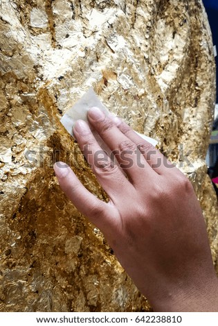 People hand is covering gold leaf to Battlements Thai in temple at Thailand. Also called Se-Ma.