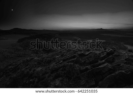 Wild rocks in popular natural park, pines on sandstones rocks above deep misty valley. Blue sky, creamy fog in valley below. Black and white photography