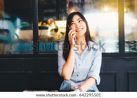 Girl calling on phone and looking outdoors background with window in the cafe
