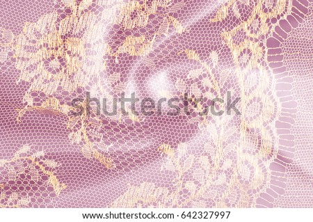Image texture background, decorative gold lace with pattern. Golden vintage lacy background. Gold lace on a pink background. Spandex, macro. Lacy decorative floral pattern.