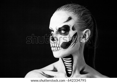 Girl with creative halloween face art on black background.