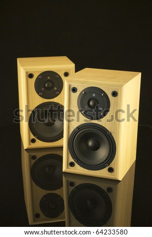 Royalty free stock image of a pair of speakers against black and on a black reflective surface with copy space above