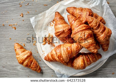 freshly baked croissants on grey wooden table, top view Royalty-Free Stock Photo #642373528