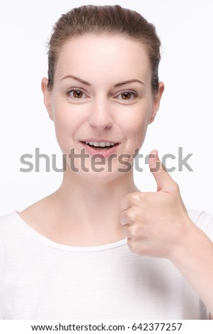 Young pretty woman in a white shirt is smiling and shows thumbs up