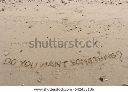 Handwriting  words "DO YOU WANT SOME THING?" on sand of beach.