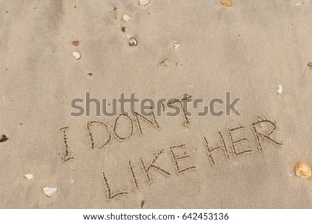 Handwriting  words "I DON'T LIKE HER" on sand of beach.
