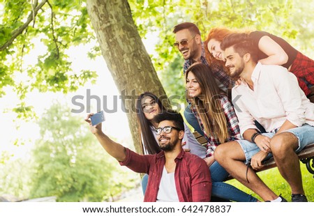Group of young people taking a selfie outdoors, having fun