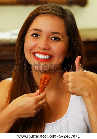 Close up of a beauty woman in restaurant approving a delicious chiken wings with a thumbs up