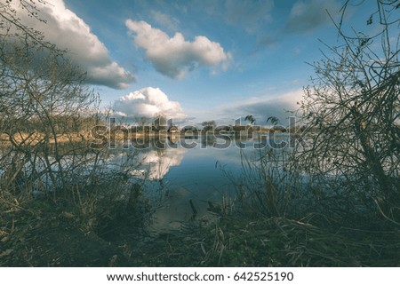 reflections of country farm house and clouds in the lake water - vintage film effect