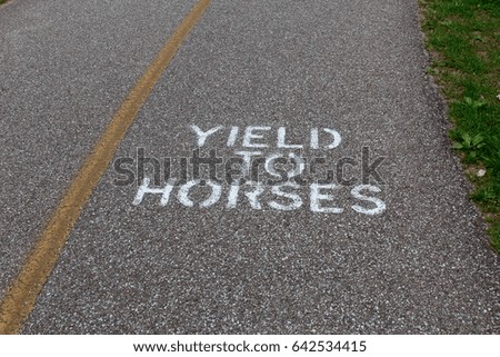 The yield to horse sign painted white on the sidewalk on a close view.
