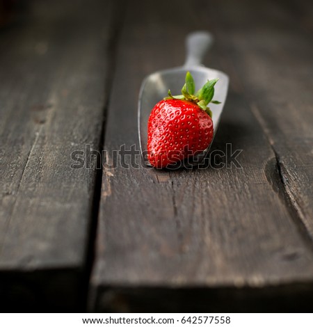 Fresh strawberries on a wooden vintage background with a vintage iron scoop. Place for text