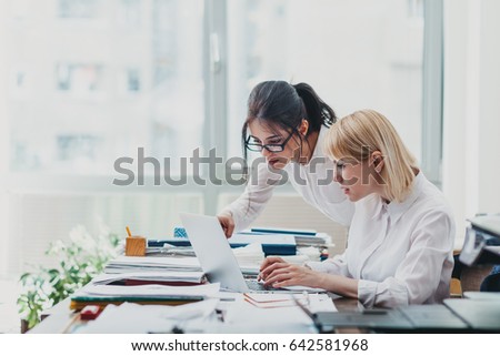 Two women in office working in front of computer