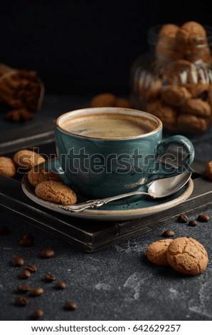 Cup of fresh coffee with Amaretti cookies on dark background, selective focus