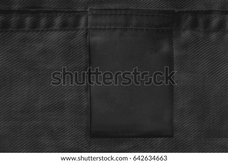 Black blank clothes label on black cloth as a background