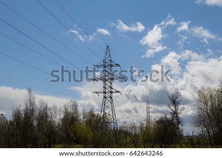High-voltage transmission lines against the blue sky with gray, gloomy clouds