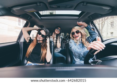 three girls driving in a convertible car and having fun Royalty-Free Stock Photo #642682015