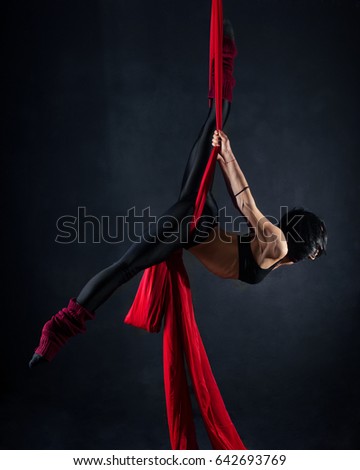The woman is engaged in aerial acrobatics on a dark background.