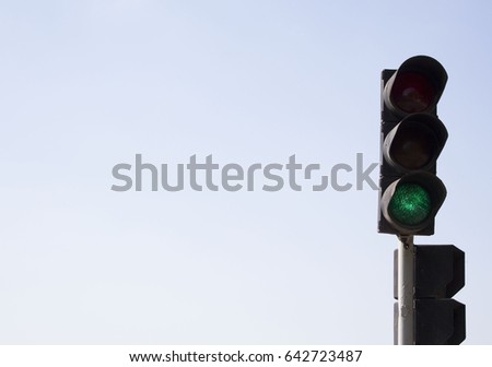 Traffic lights with green sign. On blue sky background. 