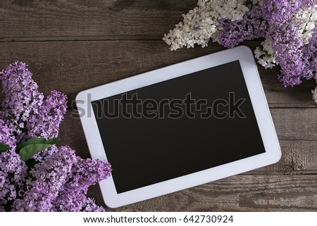 Lilac blossom on rustic wooden background, tablet with empty space for greeting message. Top view
