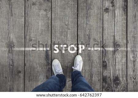 Man standing on the wooden boards with stop message on the floor, point of view perspective used. Royalty-Free Stock Photo #642762397