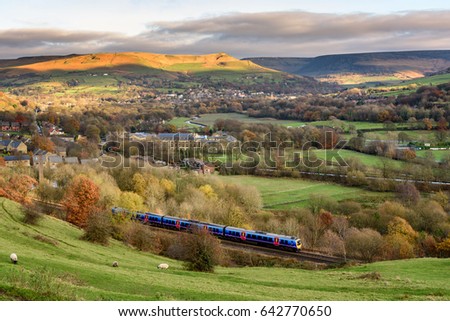 Passenger train passing through british countryside near greater Manchester, England. Royalty-Free Stock Photo #642770650