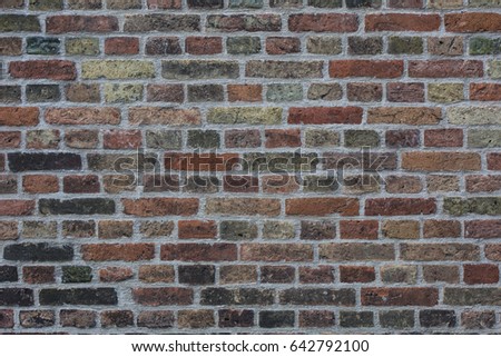 Wall made from red and sometimes colorful bricks of regular shapes and random distribution slotting together precisely. Close up architecture photography. Creative wallpaper photography.