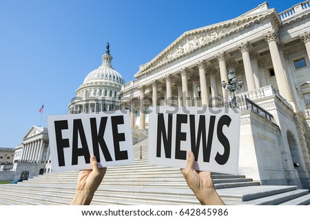 Hands holding signs protesting fake news coverage in front of the Capitol Building in Washington DC, USA