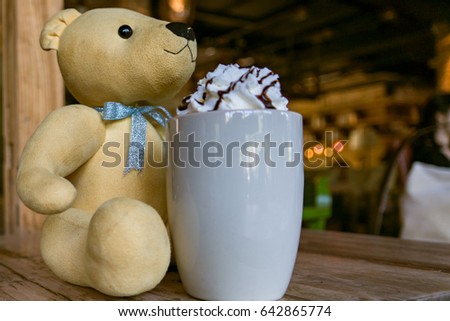 a light brown cute bear with a hot mocha coffee with whipping cream on the wooden table  - apply filter