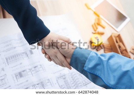 Two confident businessman shaking hands during a meeting in the office, success, dealing, greeting and partner concept. with blurred background of contractor use effect. engineer, woman, architect.