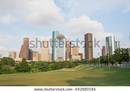 Downtown Houston at sunset with people exercising in distant. Green park lawn and modern skylines. The most populous city in Texas, and fourth-most in United States. Architecture and travel background