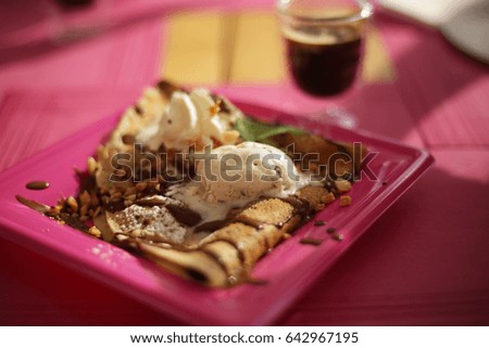 Pancake served with a ball of ice cream, walnuts, chocolate and mint leaves