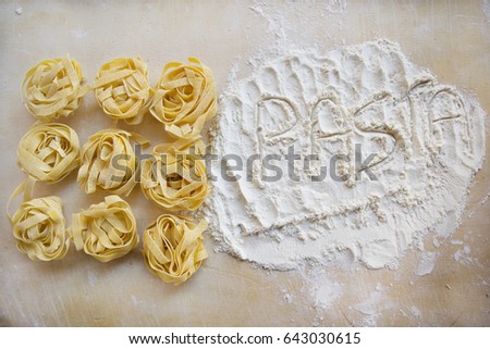 the word pasta written with the flour next to some tagliatelle
