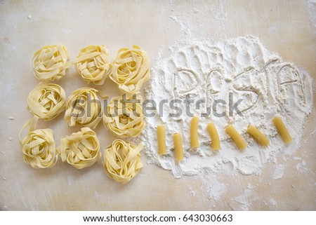 the word pasta written with the flour next to some tagliatelle