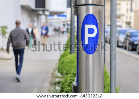 Stainless steel parking meter and bustle of blurred people on the sidewalk