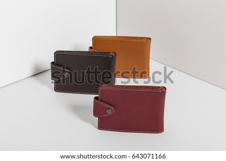 three leather wallet closed on the grey background.