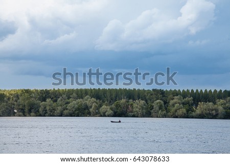 Picture of a boat on a canadian style lake, during a cloudy afternoon
