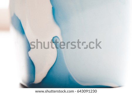 Close up of a white cup with a home made blue nail polish decoration
