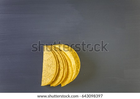 Yellow corn taco shells on a gray background.