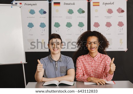 Smiling boy and girl with thumbs up during language lesson/Boy and girl during language lesson/Sunny, partly cloudly,cloudly, rainy, snowy, sleeting, icy, tornado, thumder